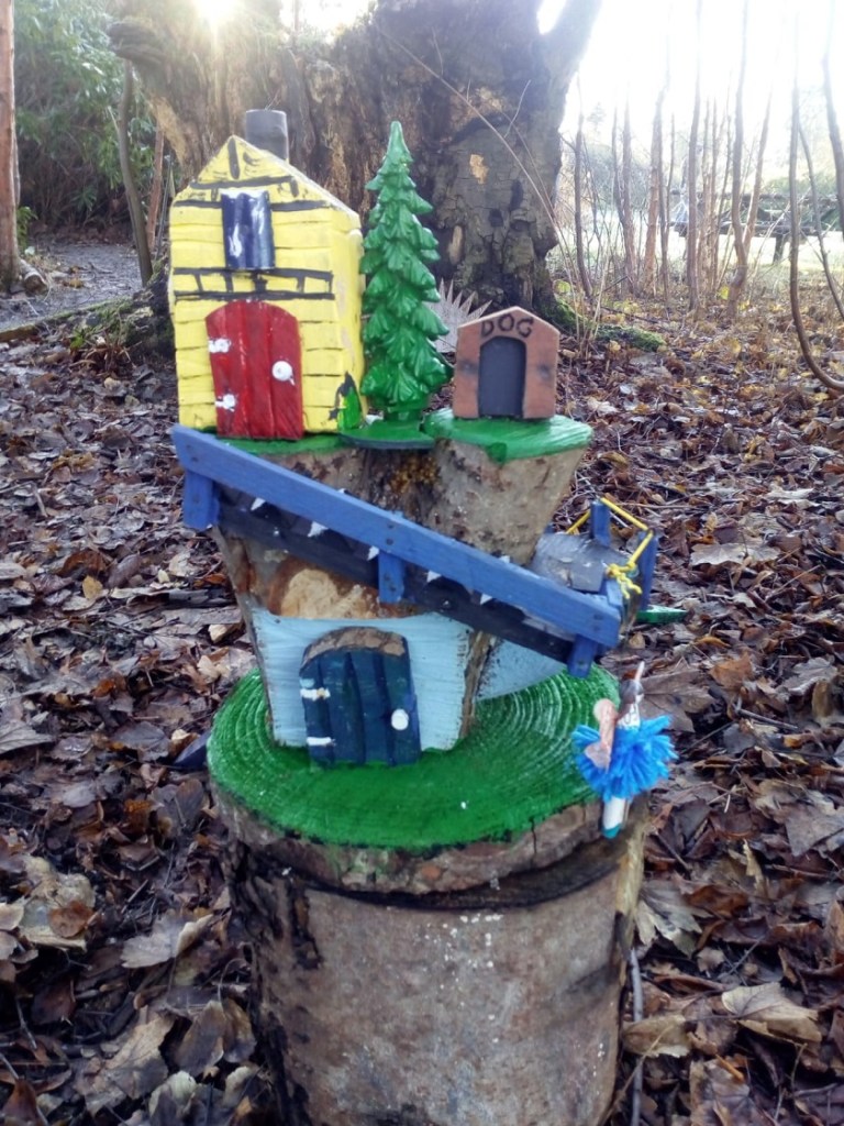 A tiny wooden house with a tree and doghouse