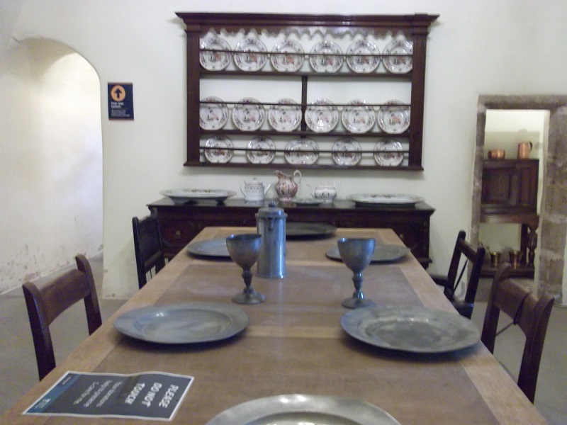 A kitchen with ancient plates and a dresser of plates beyond it