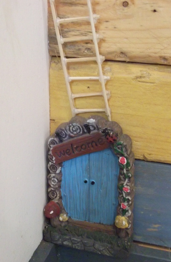 A blue fairy door with steps leading upwards