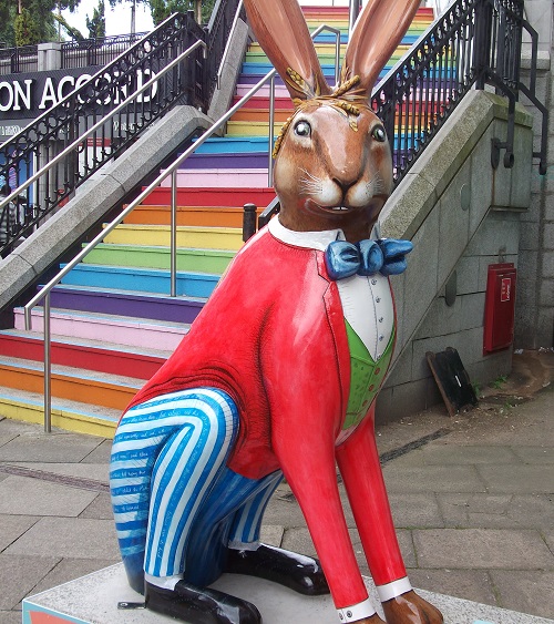 a hare sculpture with a red jacket, blue bowtie and blue and white striped trousers