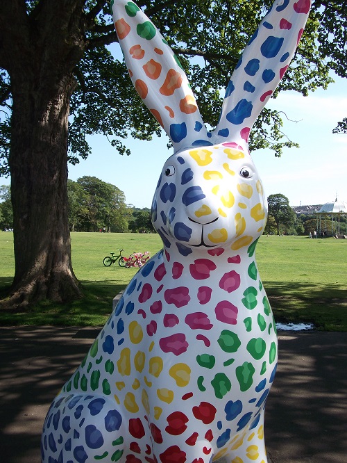 a hare sculpture with bright orange, yellow, blue, pink and green dots