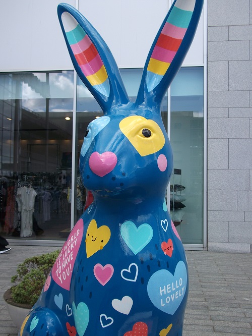 a painted hare sculpture with a blue body and painted hearts all over it