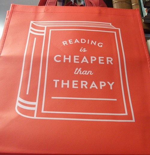 A shopping bag with the text Reading is Cheaper than Therapy