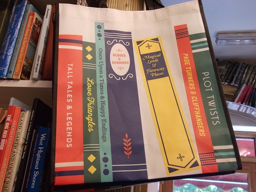 A shopping bag with pictures of books, with titles including Tall Tales and Legends, Plot Twists, Magical Lands and Faraway Places.
