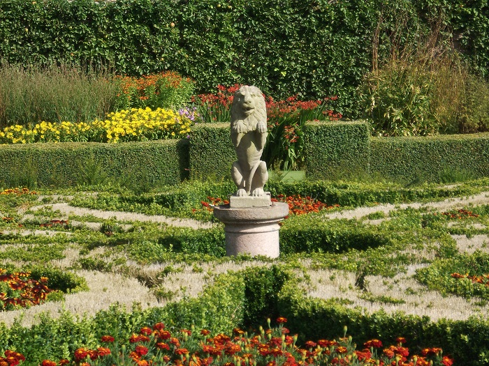 a statue of a lion in the middle of box hedge parterres
