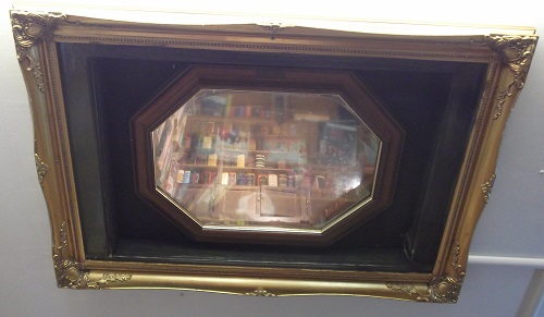 A mirror with a picture of bookshelves inside.