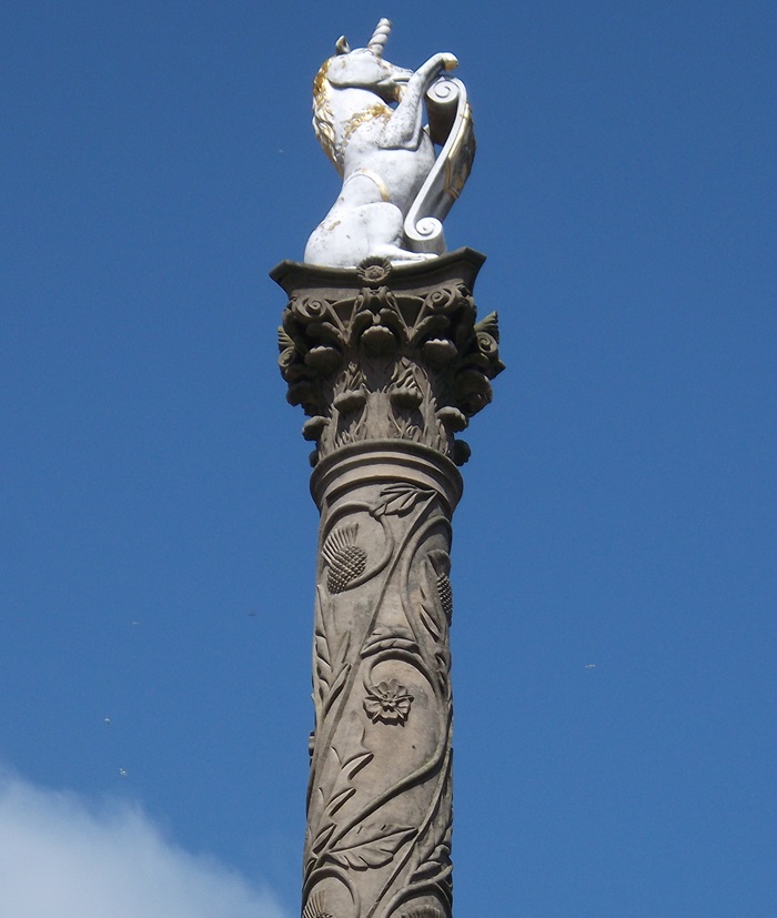 white unicorn on its haunches and holding a scroll, on top of a stone plinth