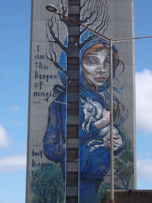 A girl in blue sweater holding a tiny unicorn with a long horn. The picture says I am the keeper of magic but happy to share