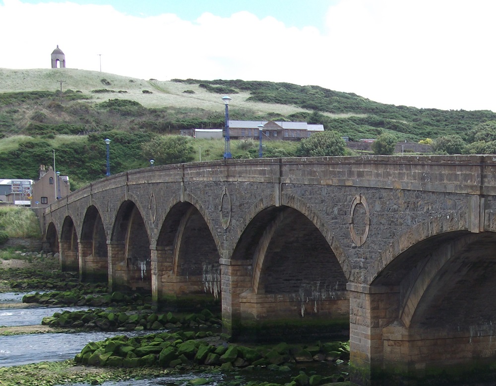 a seven arched bridge with a monument on a hill beyond