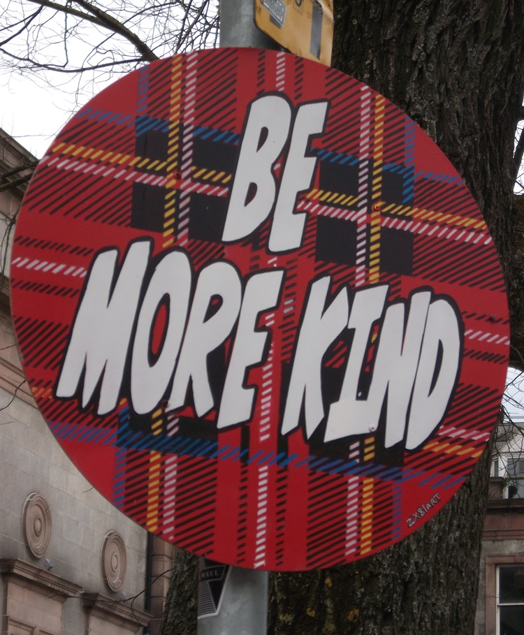 A round tartan plaque states Be More Kind