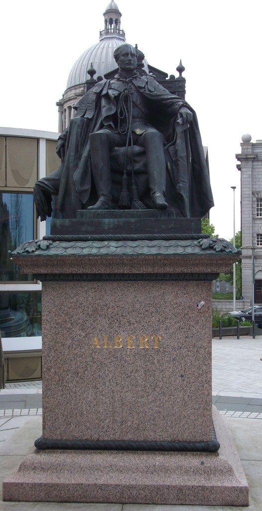 A statue of a man in long flowing robes on a chair
