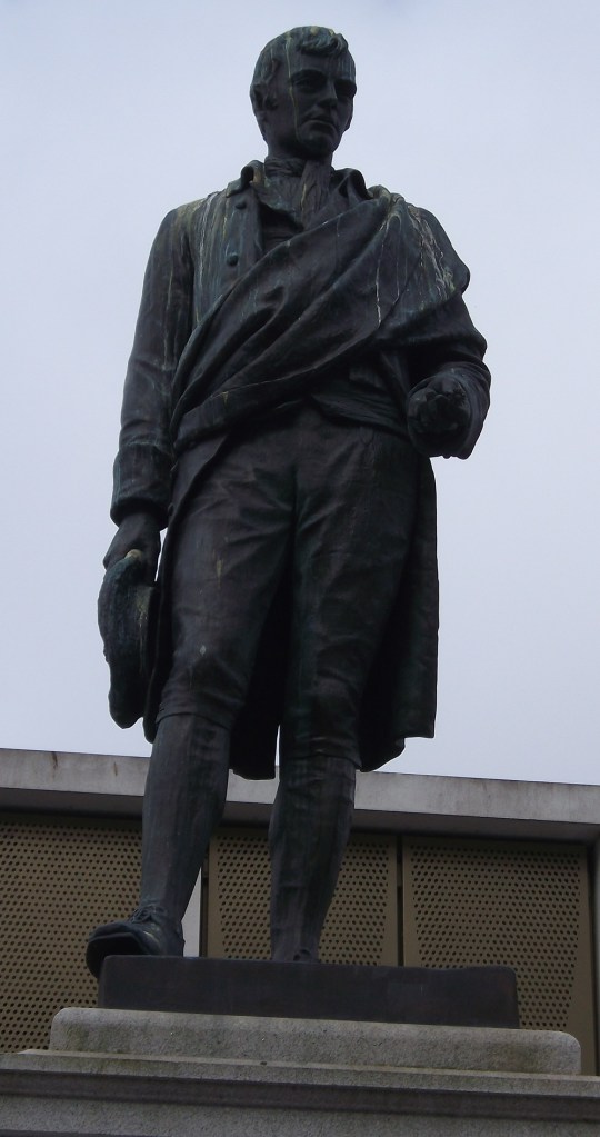 Statue of a man with long jacket holding a daisy