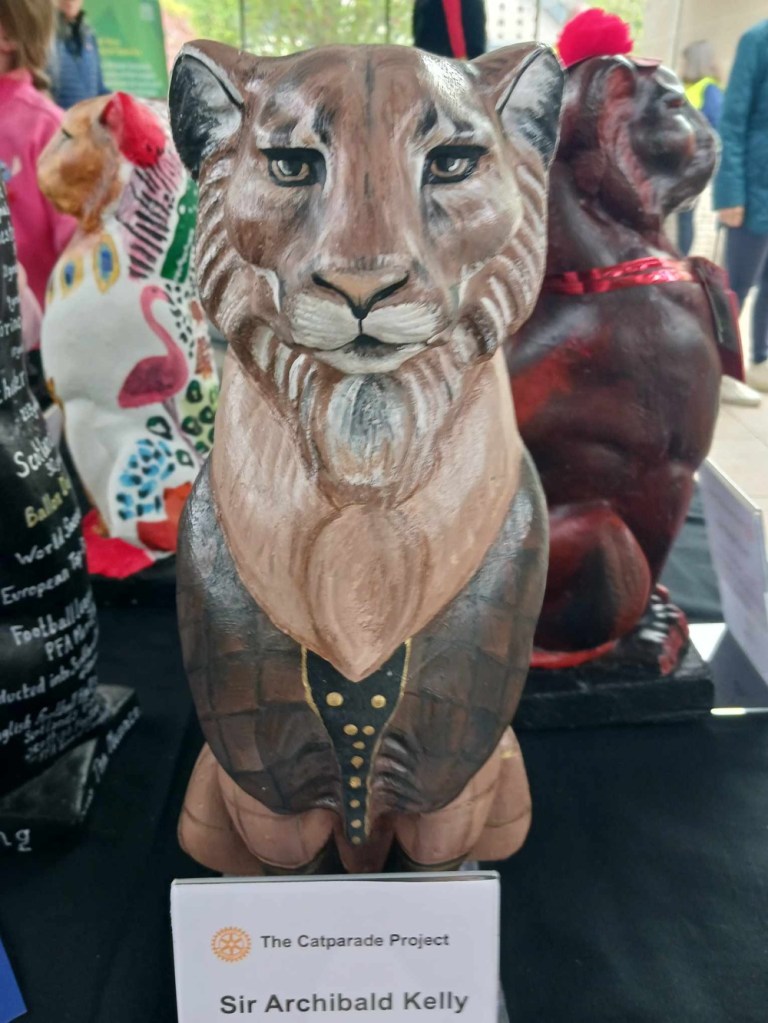 A brown cat statue with mane and waistcoat