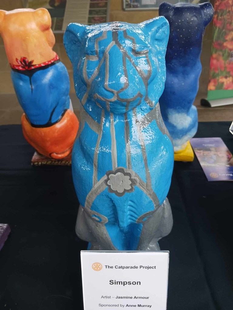 A blue cat statue with grey lines painted over it