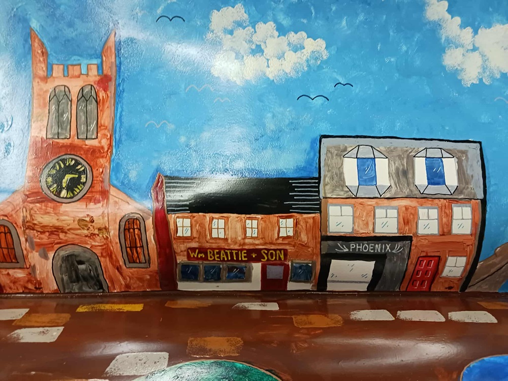 A painting of a village street with church, shop and house with Phoenix sign