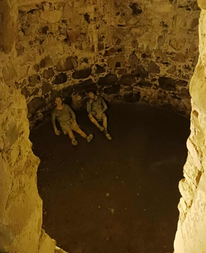 A dark stone dungeon with two mannequins lying below