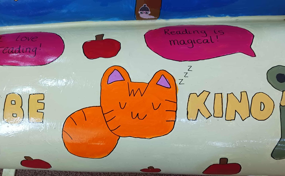 A ginger cat with a pink thought bubble that states Reading is Magical!