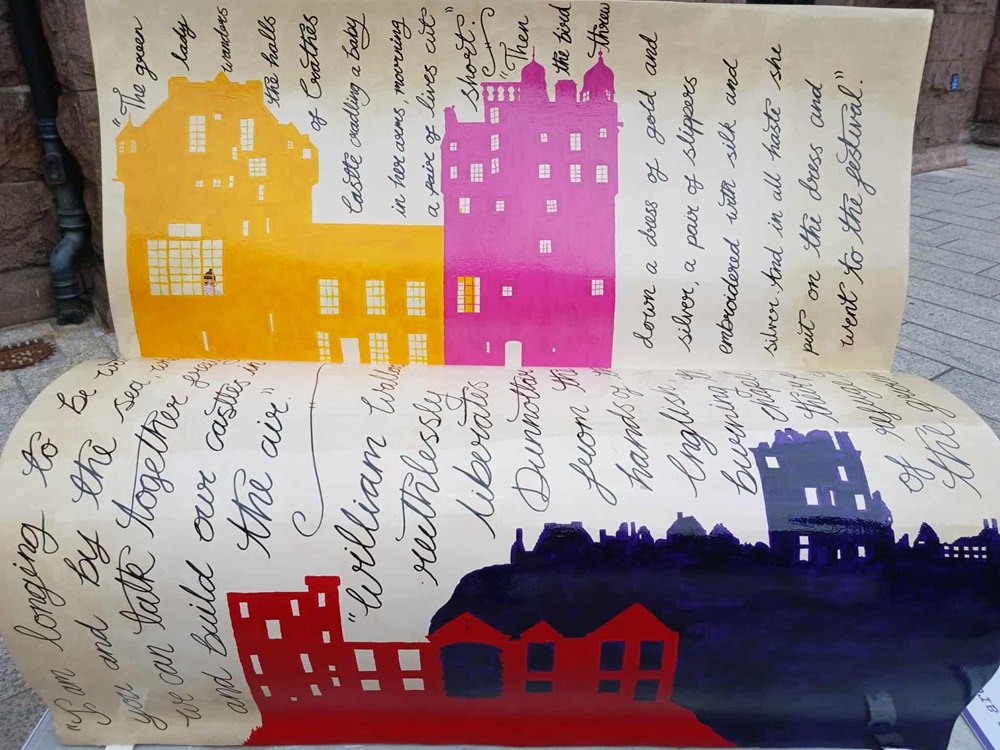 a white bench with oldfashioned handwriting and pictures of a yellow, pink and blue castle