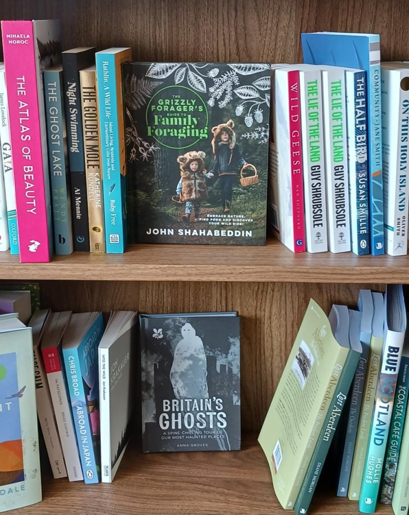 Colourful books on a shelf, one is facing forwards and the title reads Grizzly Forager's Guide to Family Foraging