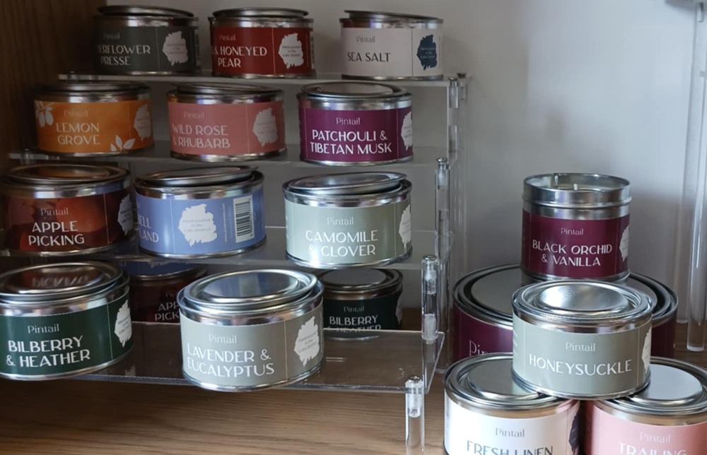 candles in different coloured tins, including burgundy Patchouli and Tibetan Musk and grey Lavender and Eucalyptus