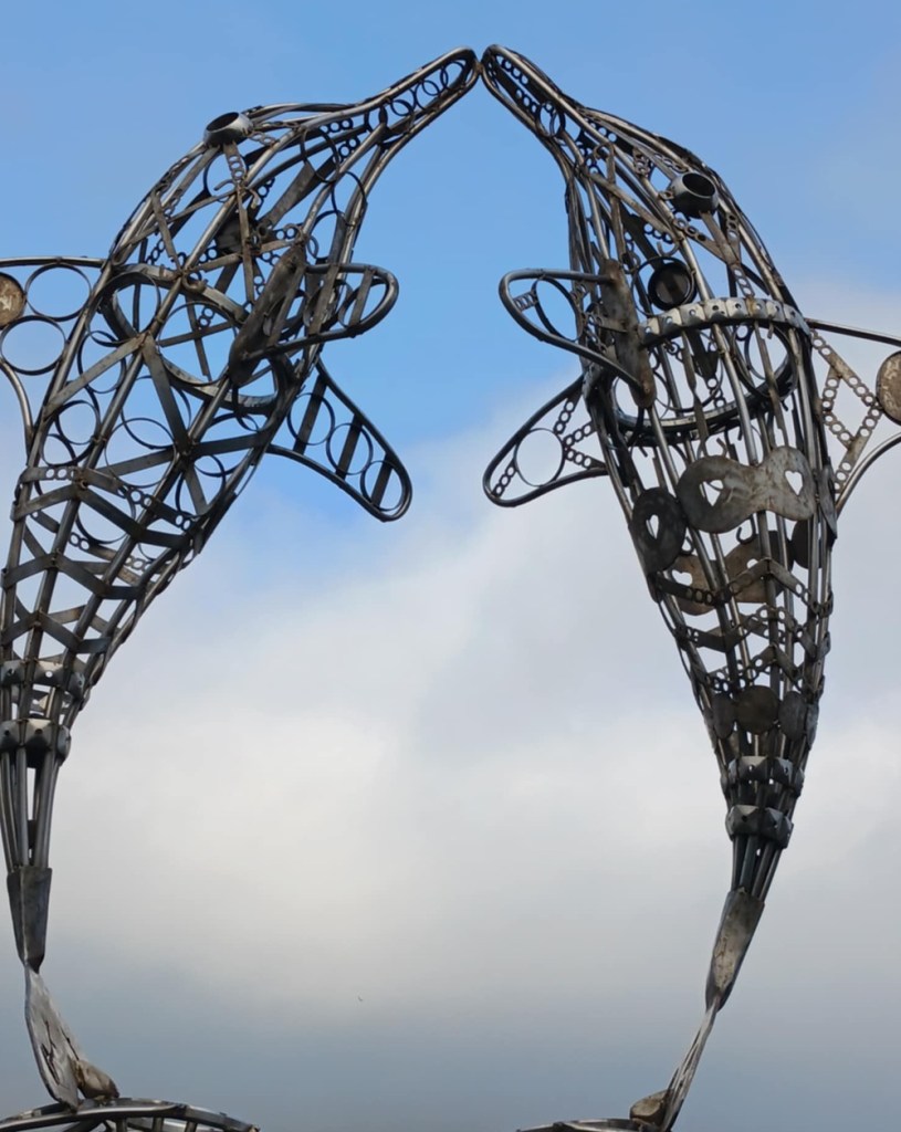 A sculpture of two dolphins with noses touching