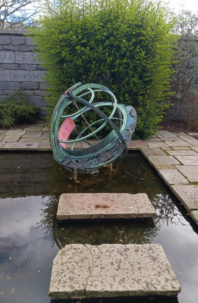 A green orb sculpture in a pond