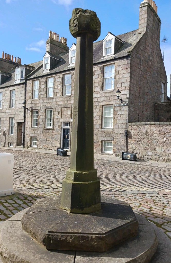 A small stone pillar with a fragment of the original Mercat cross on top