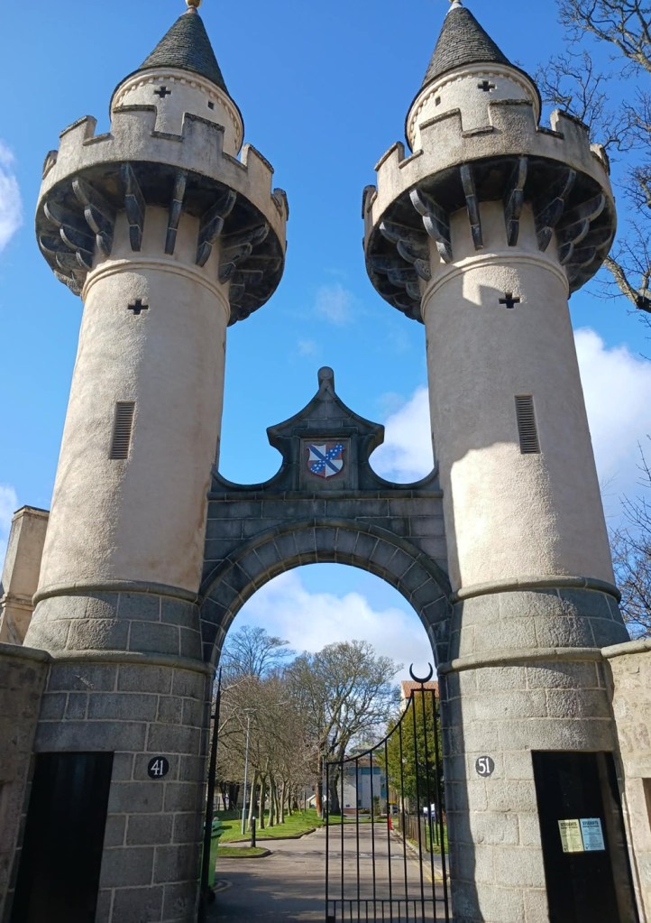 turreted circular columns above a crested archway and gate