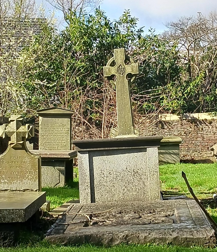 A cross towers over a gravestone