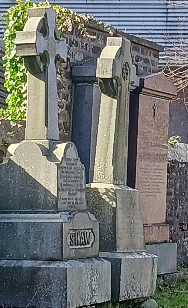 Three old grey gravestones against a wall