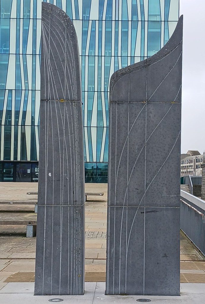 Two tall thin grey columns featuring engraved lines and curved at the top.