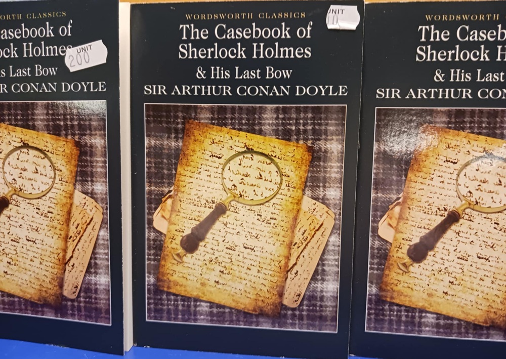 A black book titled The Casebook of Sherlock Holmes and His Last Bow with a picture of parchment and a magnifying glass