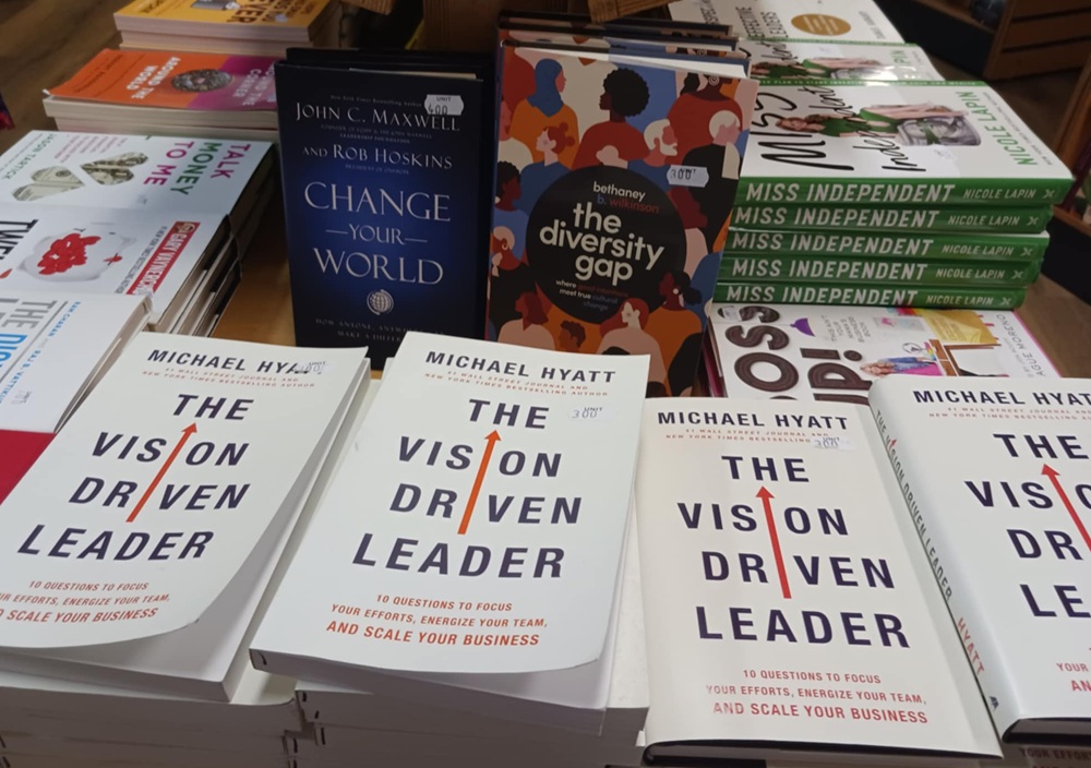 A selection of books including several white books titled The Vision Driven Leader