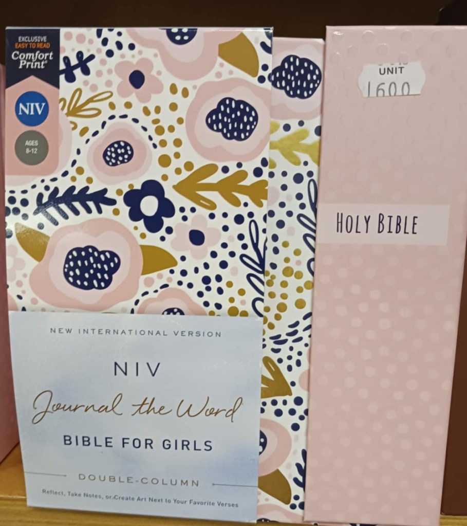 A pink Holy Bible with pink and blue shapes on its cover