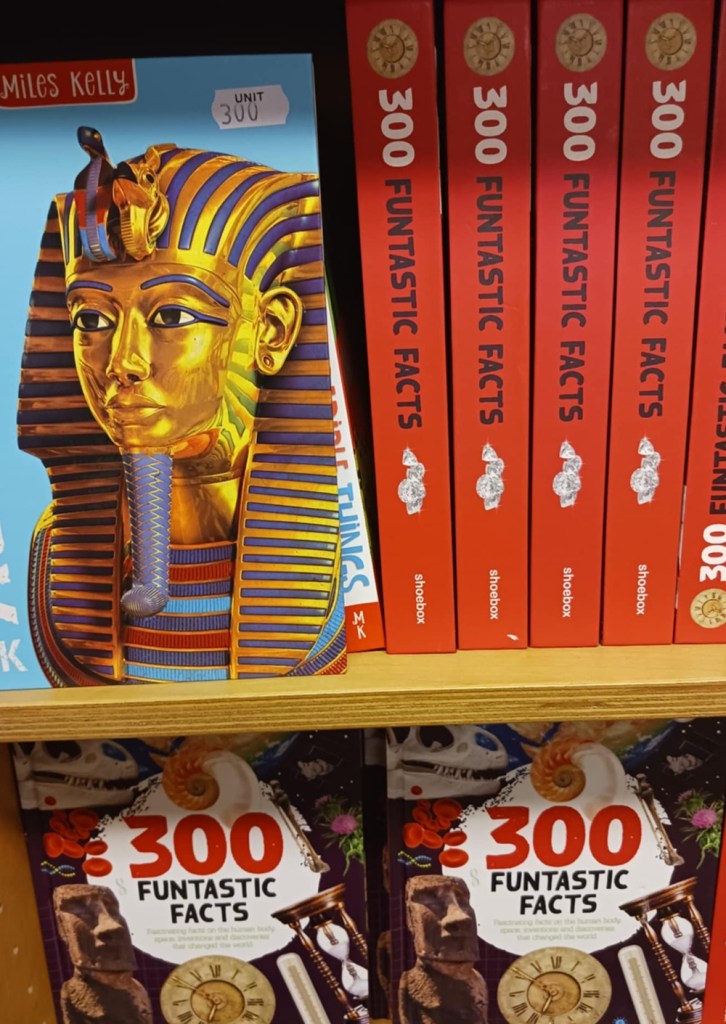 A book depicting an ancient Egyptian in headdress next to four orange books with title 300 Funtastic Facts viewed side on and below viewed face on with pictures including a dinosaur skull and Easter Island statue